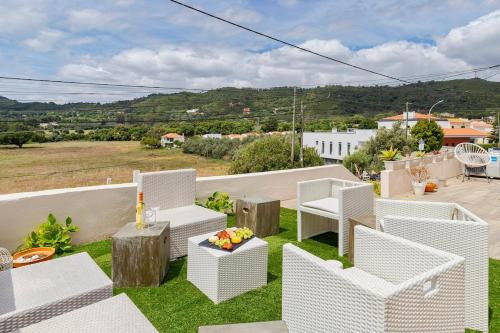 a patio with white chairs and tables on the grass at Lovely Villa - By Y Concept in Setúbal