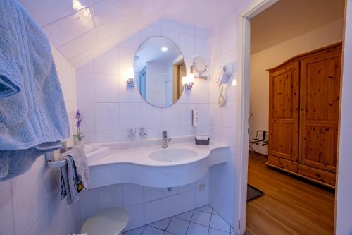a white bathroom with a sink and a mirror at Hotel Schlösschen Sundische Wiese Zingst in Zingst