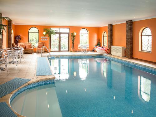 a large swimming pool in a room with orange walls at Lambourne House - Ukc2831 in Skegness