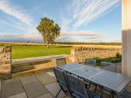 a patio with a table and chairs and a field at Broomrigg Farmhouse in Pencaitland