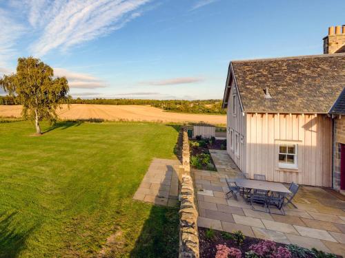 a house with a bench next to a field at Broomrigg Farmhouse in Pencaitland