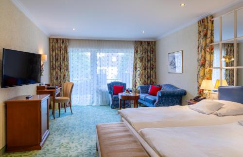 a hotel room with two beds and a flat screen tv at Relais & Châteaux Hotel Schwarzmatt in Badenweiler