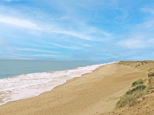 a sandy beach with the ocean in the background at Painter's Cottage in Hemsby