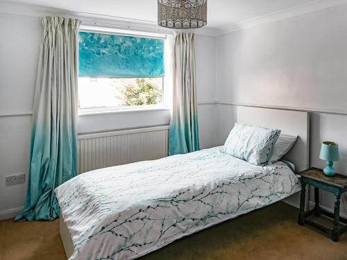 a bedroom with a bed and a window at Painter's Cottage in Hemsby