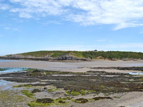a sandy beach with a hill in the background at Quayside in Cemaes Bay