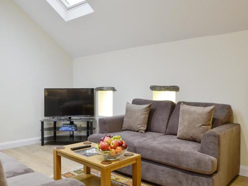 a living room with a couch and a table with a bowl of fruit at Mary Rook Cottage - Uk1369 in Keswick