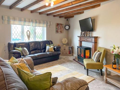 a living room with a leather couch and a fireplace at Ash Cottage E1224 in Addlethorpe
