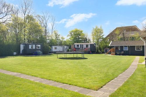 a large grassy yard with a picnic table and trailers at Camping Oudesluis in Oudesluis