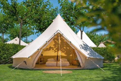 a white tent with a bed in the grass at Somo Bungalow Resort - Camping Latas in Somo