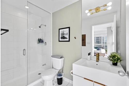 a white bathroom with a toilet and a shower at Toronto Harbourview Suites with free parking in Toronto