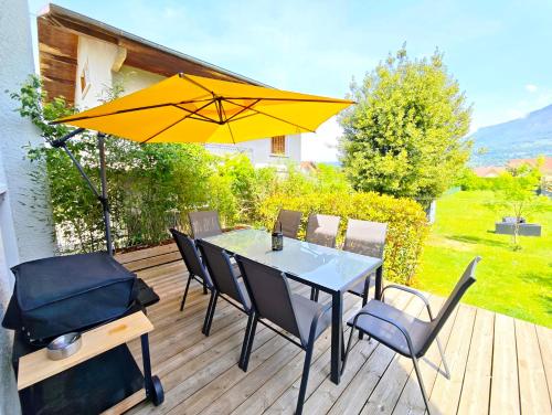 a table with chairs and an umbrella on a deck at Maison chaleureuse - Proche du lac in Tresserves