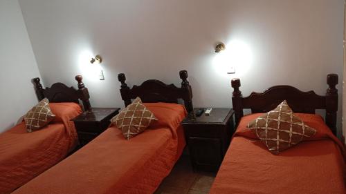 a bedroom with two beds with orange sheets and pillows at Ragas in Palma Sola