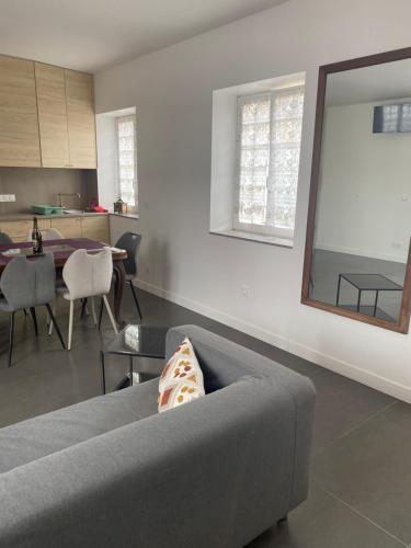 a living room with a gray couch and a mirror at Charmant maison in Pontorson