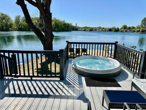 a hot tub sitting on a deck next to the water at Exclusive Lakeside Holiday Lodge with Hot tub and Private Fishing Peg at Tattershall Lakes in Tattershall