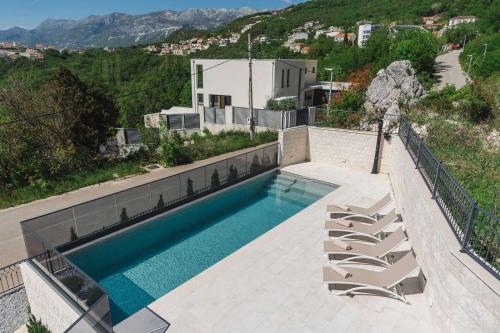 a swimming pool with lounge chairs and a house at Boutique Villa Levante in Blizikuće