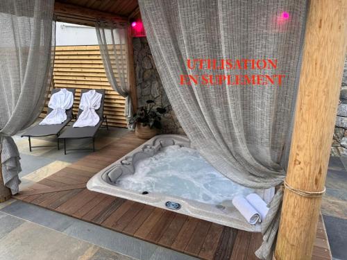 a hot tub on a deck with chairs and a sign at Auberge Desprairies in Saint-Joseph