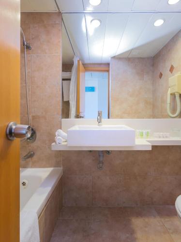 a bathroom with a sink and a tub and a mirror at Prima City Hotel in Tel Aviv
