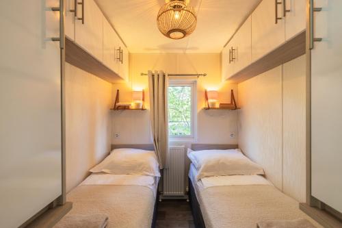 a row of beds in a room with a window at Sfeervol boshuisje op de Veluwe Vossenberg in Nunspeet
