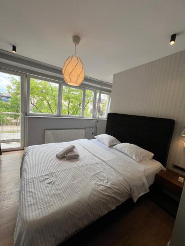 a bedroom with a large white bed with windows at Boulevard Studios NewBorn in Prishtinë