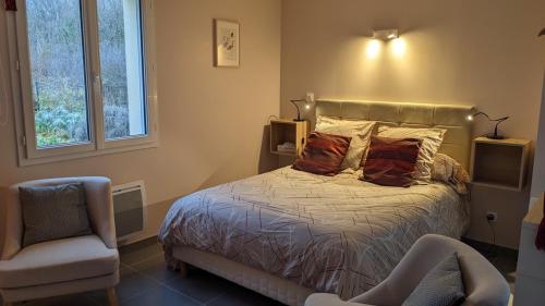 a bedroom with a bed and a chair at Gîte de la Pinsonnerie in Fondettes