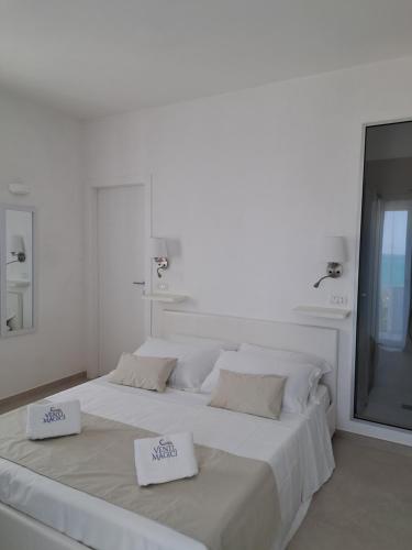 a white bedroom with a large bed with two towels on it at Venti Magici Rooms in Peschici