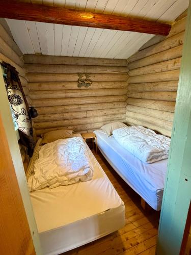 two beds in a room with wooden walls at Grasbakken hytteutleie in Nesseby