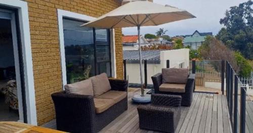 a patio with two chairs and an umbrella at Hartmel Sea Deck in Hartenbos