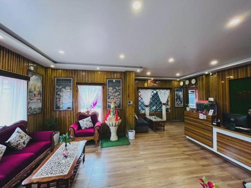a living room with purple couches and a flat screen tv at Hotel Aanandalok in Pānigata