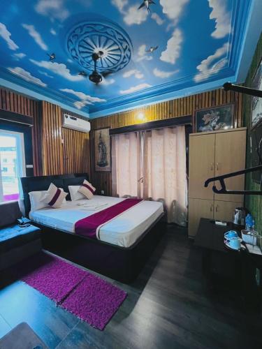 a bedroom with a large bed with a blue ceiling at Hotel Aanandalok in Pānigata