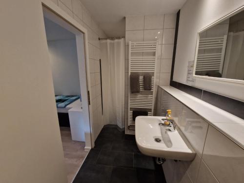 a white bathroom with a sink and a mirror at Pension Assenheim in Assenheim