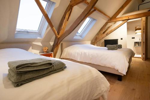 two beds in a attic room with skylights at Herberg 't Molenhuis in Vichte