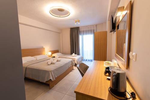 a hotel room with two beds and a desk at Cynthia in Nea Vrasna