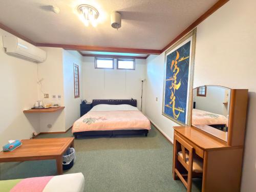 a bedroom with a bed and a desk and a mirror at ペンションminiモンゴル in Makito