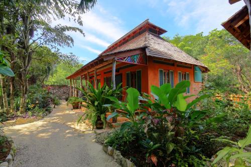 a small red house in the middle of a garden at Tingalaya's Retreat in Negril