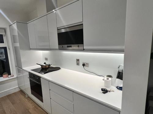 a kitchen with white cabinets and a stove top oven at Modern Townhouse Birmingham in Birmingham