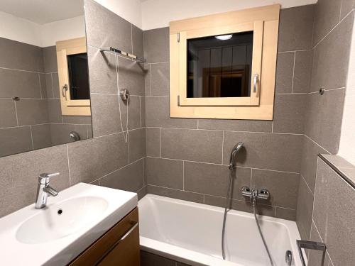 a bathroom with a sink and a bath tub at Chesa Silvretta - Celerina in Celerina