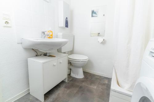 a white bathroom with a toilet and a sink at fewo1846 - Smutjes Koje - für eine entspannte Auszeit mit Balkon im Stadtzentrum in Flensburg