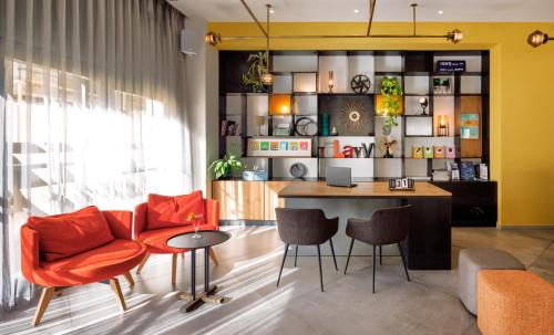una oficina con sillas naranjas, escritorio y mesa en Prima City Hotel en Tel Aviv