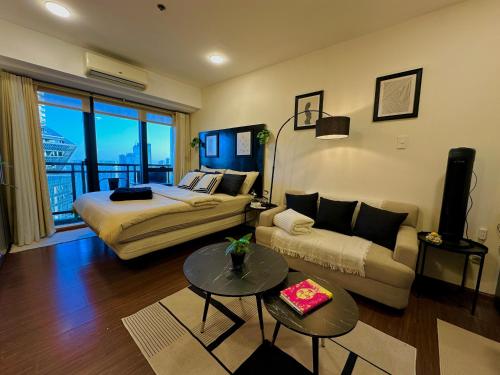 a bedroom with a bed and a couch and a table at Knightsbridge Residences in Manila