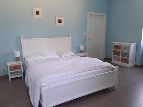 a bedroom with a white bed with two night stands and two tables at Le Gite des Sources in Lormes