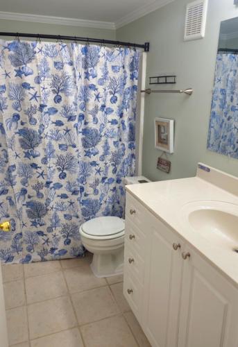 a bathroom with a toilet and a blue and white shower curtain at Tiny Palace - 1-Bedroom Apartment - Multi-Week Stay - Pool - Washer-Dryer - Dog-friendly with fee for 1 Family Pet in Wilmington