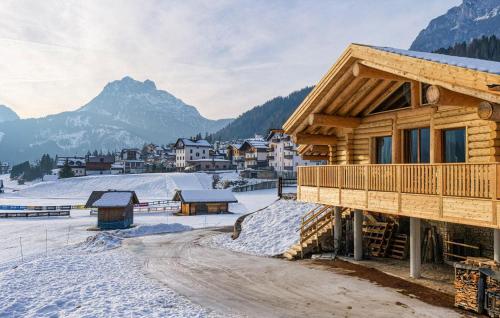 a log cabin in the snow with mountains in the background at Gorgeous Home In Sappada With Sauna in Sappada