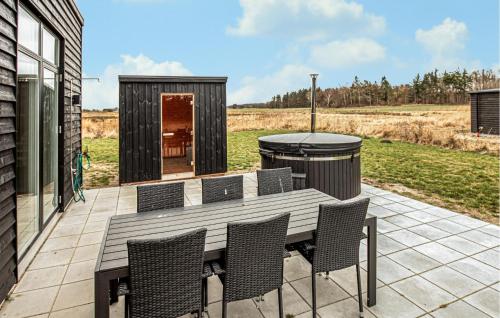 a wooden table and chairs on a patio with a grill at Gorgeous Home In Grenaa With Sauna in Grenå