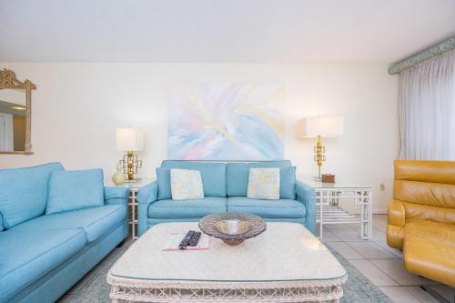 a living room with blue couches and a table at Driftwood Towers 6D condo in Gulf Shores