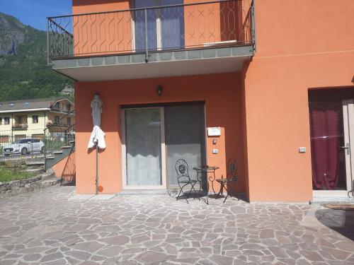 an orange building with a balcony and a table on a patio at La Rosa di Emma in Porlezza