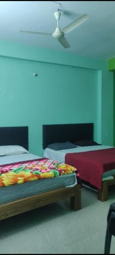 a bedroom with two beds and a blue wall at HOTEL SEA ROCk in Belagula