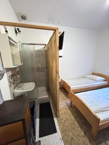 a small room with a bed and a sink and a mirror at Sobe Kovacevic in Cvijetići