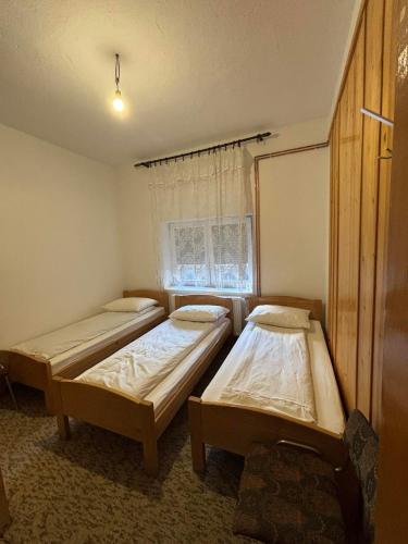 two beds in a room with a window at Sobe Kovacevic in Cvijetići