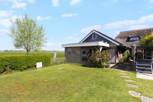 a house with a grass yard in front of it at De Zilverreiger op camping Oudesluis in Oudesluis