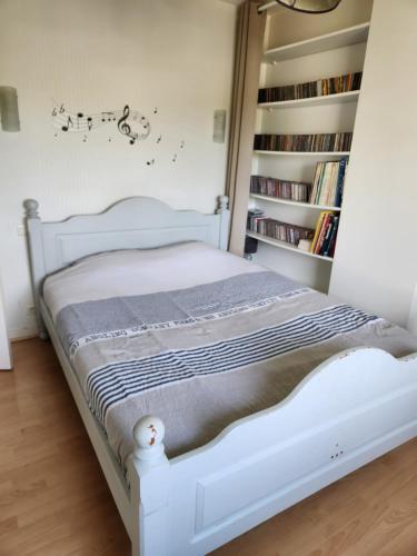 a white bed in a room with a book shelf at Charmante maison in Dinard